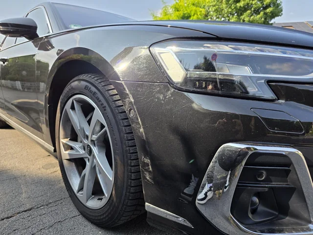 Beschädigter vorderer Stoßfänger eines grauen Fahrzeugs