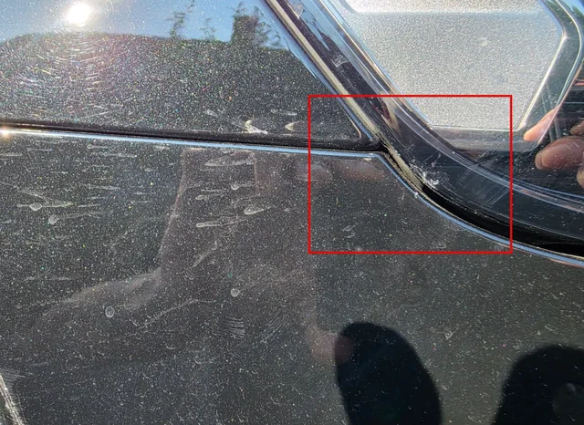Rot markierter Riss am Scheinwerferglas eines dunklen Fahrzeugs